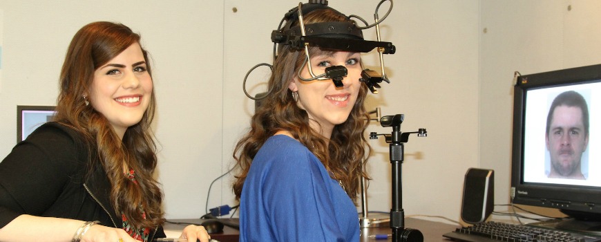Two students smiling, while one has testing equipment over her head